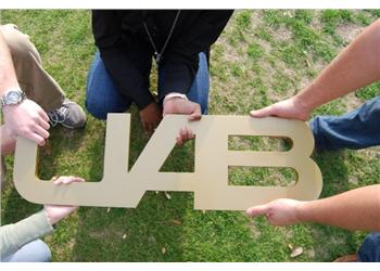 people holding uab letters on grass