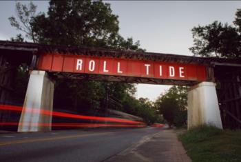 railroad bridge with 'roll tide' over a street at dusk