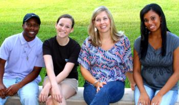 four people sitting on steps outdoors smiling