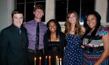 group of five smiling people standing indoors