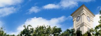 clock tower against a blue sky with fluffy clouds