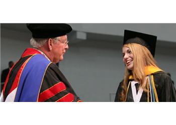 graduate smiling at faculty in regalia