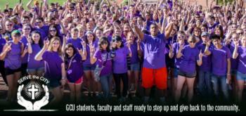 group of people in purple shirts with 'serve the city' banner