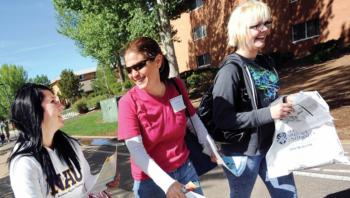 three students smiling and walking on campus