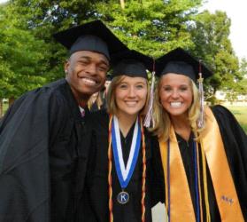 three graduates smiling outdoors