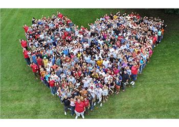 group of people forming a heart shape on grass