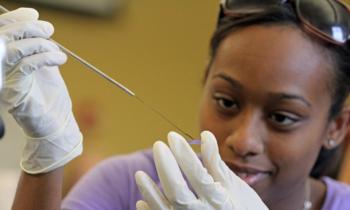 student in lab gloves handling a pipette