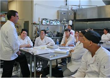 instructor speaking to culinary students in kitchen classroom