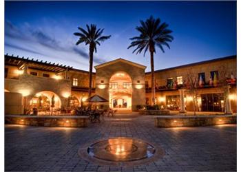 twilight view of a courtyard with palm trees and a fountain