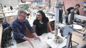 instructor discussing a project with a student over a workbench