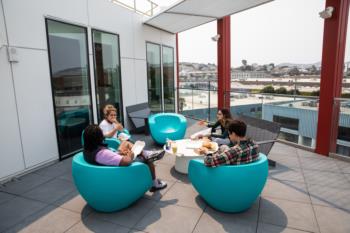 students studying on a balcony with round blue chairs