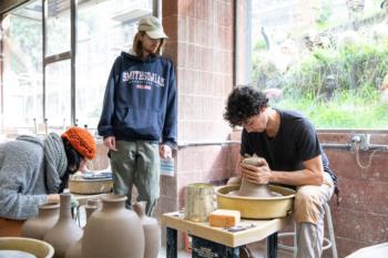 two students working with pottery in a workshop