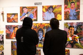 two individuals observing colorful illustrations on a wall