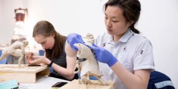 students sculpting anatomical figures at a workshop table