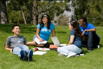 students on grass with laptops, 'CSUSB' on shirt
