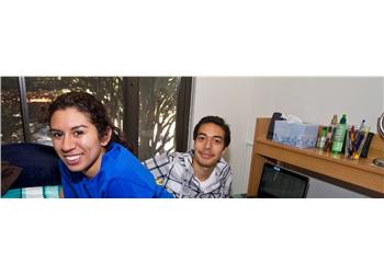 two students smiling in a dorm room