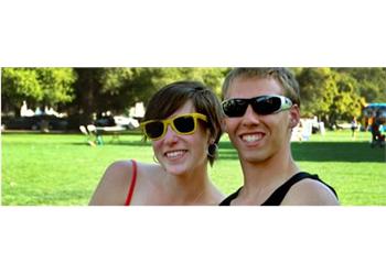 two people smiling with sunglasses outdoors