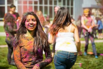 students with colorful powder on clothes at outdoor event