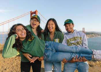 students posing near golden gate bridge with one being carried