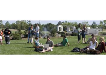 students relaxing and socializing on a grassy campus area