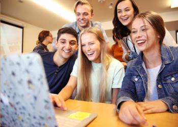 group of students smiling at a computer