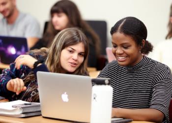 two students studying together with a laptop