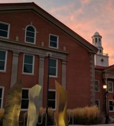 brick building with clock tower at dawn/dusk and sculpture