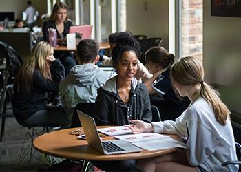 students studying inside campus building at round tables