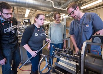 students and faculty analyzing equipment in engineering lab