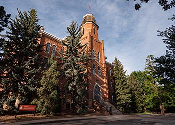 historic campus building with towering spire and trees