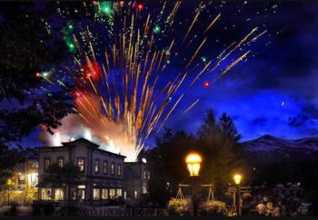 fireworks display over a town at night with mountains