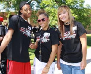 three students in black t-shirts smiling outdoors