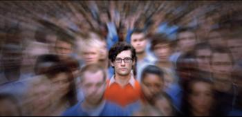 man in glasses centered with blurred people around