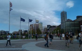 people walking across a campus plaza with flags and skyscrapers