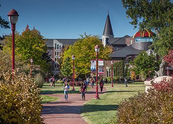 students walking on campus path with autumn foliage