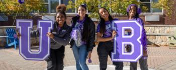 students holding letters 'U B' outdoors