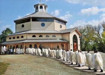 people in religious garments walking to a round building