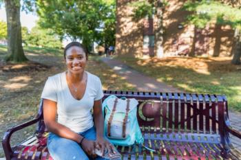 student sitting on bench with backpack