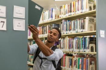 student taking book from library shelf