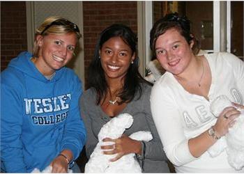 three students smiling, one wearing a college hoodie