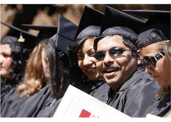 graduates in caps and gowns smiling with diploma