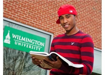 student reading a book by Wilmington University sign