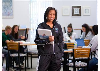 student holding a binder in a classroom setting