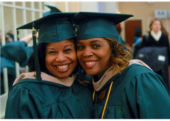 two graduates embracing and smiling