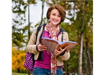 female student with bookbag and an open book outdoors