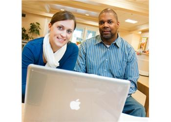 two individuals with a laptop at a table