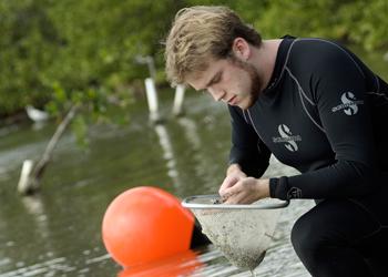 researcher outdoors with notebook and water sample