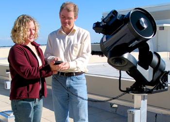 two people with a telescope on a rooftop