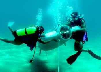 two scuba divers inspecting underwater equipment