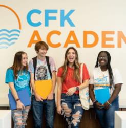 students in front of 'cfk academy' sign smiling